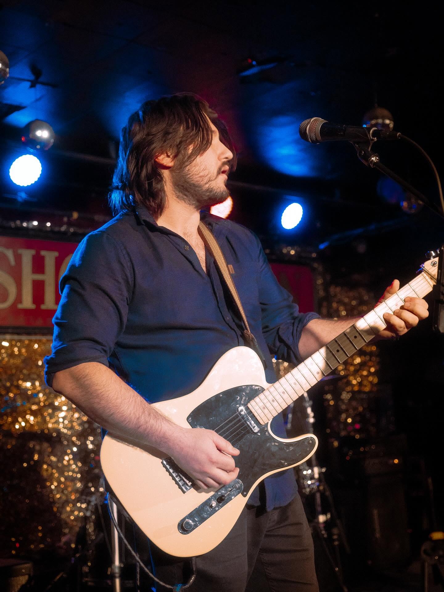 Sean playing electric guitar on stage under blue lights